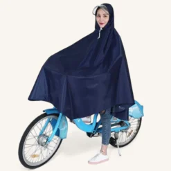 Femme joyeuse en poncho bleu sur un vélo, prête pour la pluie.