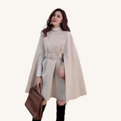 Tenue sophistiquée : cape beige, robe ajustée et bottes noires pour un look moderne.