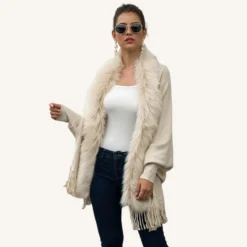 Femme élégante en cardigan beige et jeans foncés, style décontracté et chic.