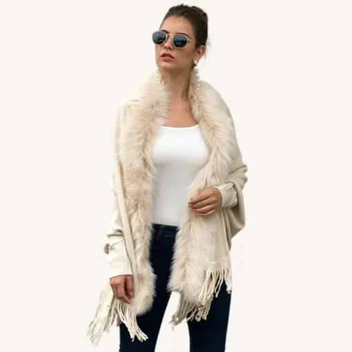 Femme élégante en shawl crème, débardeur blanc et jeans, avec accessoires modernes.