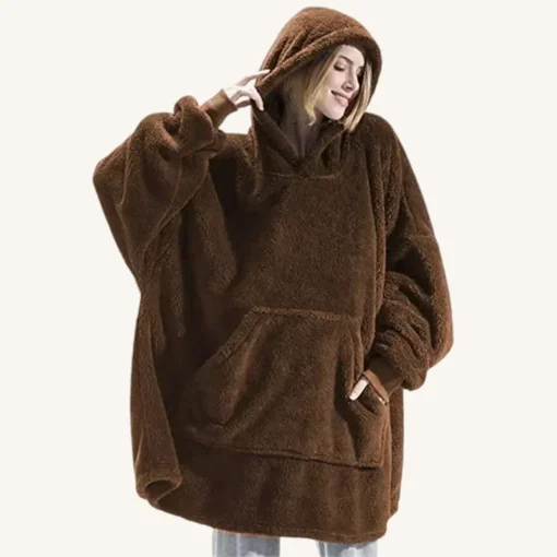 Femme joyeuse en poncho marron oversize, alliant confort et style décontracté.