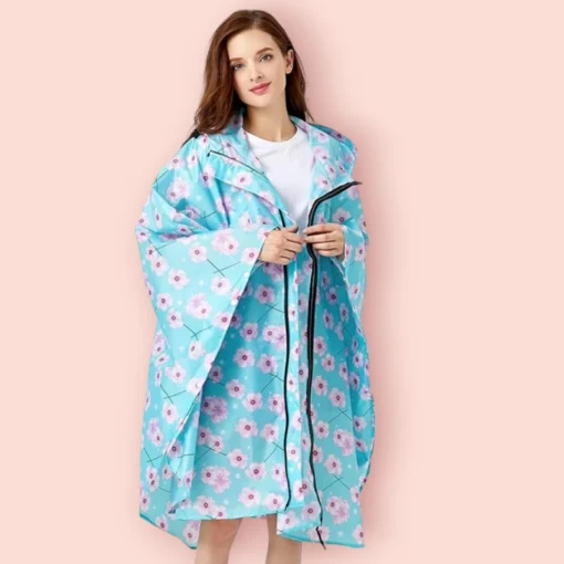 Femme souriante en imperméable floral coloré sur fond rose pastel, idéale pour les jours de pluie.