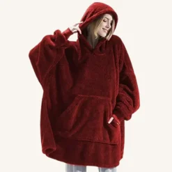 Jeune femme en poncho rouge oversized, confortable et stylé, posant avec assurance.