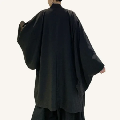 Personne en kimono noir fluide, alliant tradition et modernité, dans un décor minimaliste.